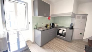 A compact kitchen with grey cabinets, a stainless steel sink, and a built-in oven. - Setúbal Downtown Todi II (Setúbal)