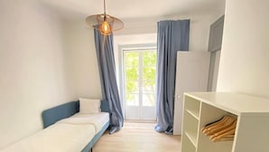 A small, well-lit room with a bed, a wardrobe, and a window with curtains. - Setúbal Downtown Todi II (Setúbal)