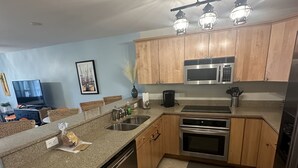 A kitchen with wooden cabinets, a microwave, an oven, and a dishwasher. - First Floor Beach Club Villa with Marsh Views - Walk to the Beach! (Saint Helena Island)