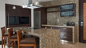 Eine moderne Küche mit Granit-Arbeitsplatten, Edelstahlgeräten und einer großen Kochinsel mit Barhocker.
