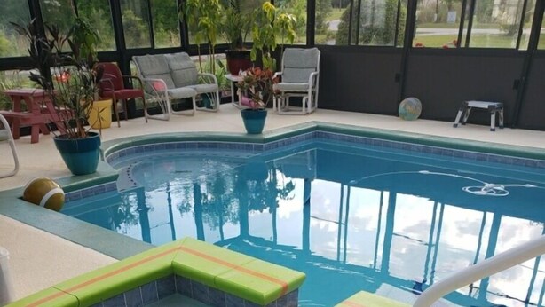 A swimming pool with a hot tub area, surrounded by lounge chairs and potted plants. - RV Executive Home #4, Indoor - Inground Pool ..Jacuzzi heated by request (Cottondale)