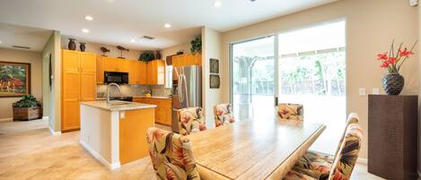Una cocina moderna con armarios amarillos, una isla central y un comedor con sillas estampadas.