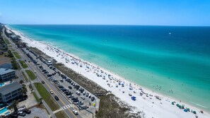 A beach with a parking lot and buildings along the shore.