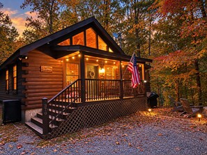 A log cabin with a porch, a flag, and a sign that reads 'Mountainside Hideout.' - ★ Prime Location ★ Fun Family Getaway ★  (Pigeon Forge)