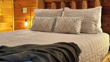 A wooden cabin-style bedroom with a bed, pillows, and a blanket.