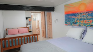 Une chambre à coucher avec un lit, un banc en bois, une échelle et un tableau représentant un coucher de soleil.