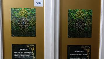 Una puerta con varios letreros, incluyendo instrucciones para el check-out, métodos de pago y una política antitabaco.
