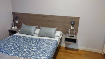 Habitación de hotel ordenada con una cama, dos mesitas de noche y un tocador.