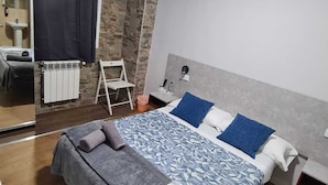 A modern bedroom with a large bed, a small desk, a chair, and a bathroom visible through a glass door. - Casa Douro (Santiago de Compostela)