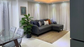 A modern living room with a sectional sofa, a glass dining table, and a large potted plant. - Penthouse Jacuzzi and Private Barbecue Exclusive (Santo Domingo)