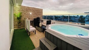 A rooftop terrace with a hot tub, seating area, and a view of the city skyline. - Penthouse Jacuzzi and Private Barbecue Exclusive (Santo Domingo)