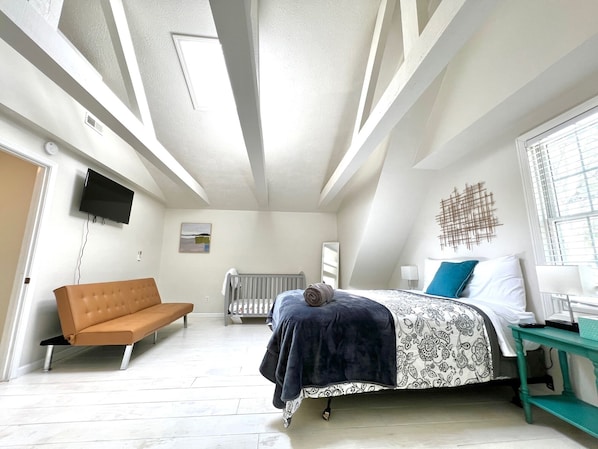 Un dormitorio con cama, sofá, televisor y ventana.