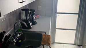 Eine moderne Küche mit weißen Schränken, einer Spüle aus Edelstahl und einer Kaffeemaschine.
