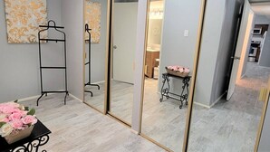 A room with a mirrored closet, a black metal rack, a small table with flowers, and a painting on the wall. - Ar`s Downtown R&R X2 A106 (Phoenix)