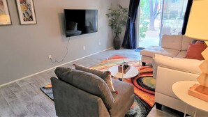 A living room with a flat-screen TV, grey sofas, a coffee table, and a colorful rug. - Ar`s Downtown R&R X2 A106 (Phoenix)