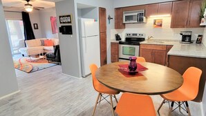 A modern kitchen with a microwave, oven, and coffee maker. There is a dining table with orange chairs and a purple vase. - Ar`s Downtown R&R X2 A106 (Phoenix)