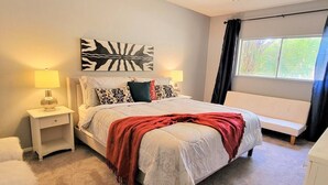 A bedroom with a bed, two bedside tables, a nightstand, a bench, a window with curtains, and a wall art piece. - Ar`s Downtown R&R X2 A106 (Phoenix)