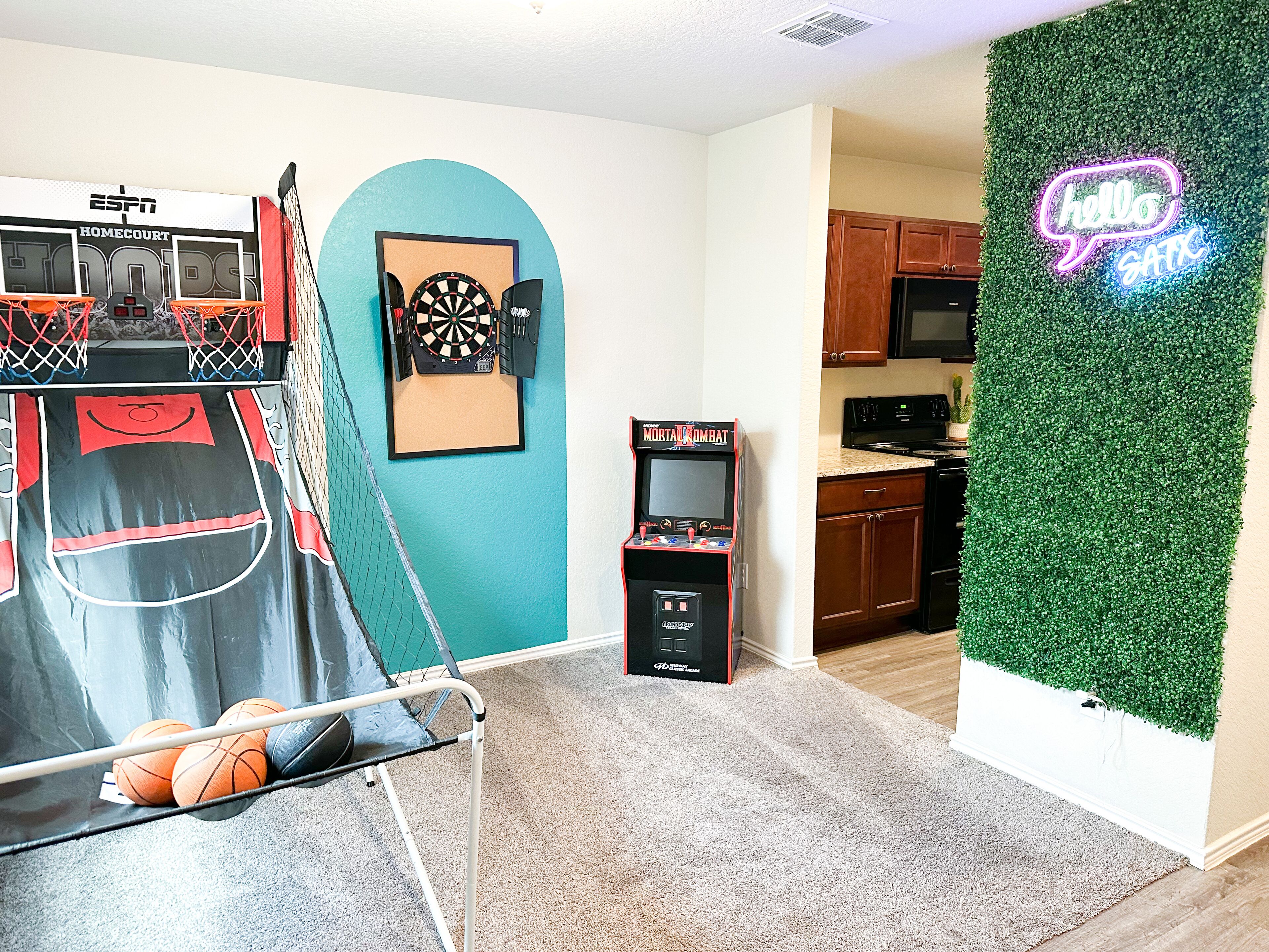 Een kamer met een basketbalring, een dartbord en een neonbord.