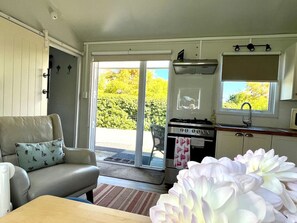 Een ruimtelijk ingerichte leefruimte met kitchenette, een eethoek en een schuifpui naar buiten.