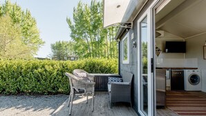 A patio with outdoor furniture, a washing machine, and a television in a residential setting.