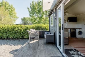 A patio with outdoor furniture, a washing machine, and a television in a residential setting.