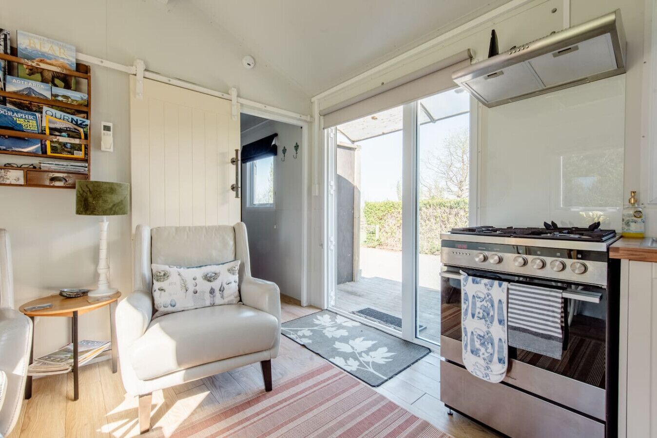 Una cocina moderna con estufa a gas, horno y un comedor con una silla y mesa.
