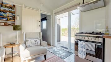 Una cocina moderna con estufa a gas, horno y un comedor con una silla y mesa.