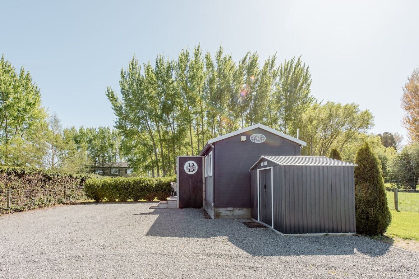 A building with a gravel driveway and a small shed.