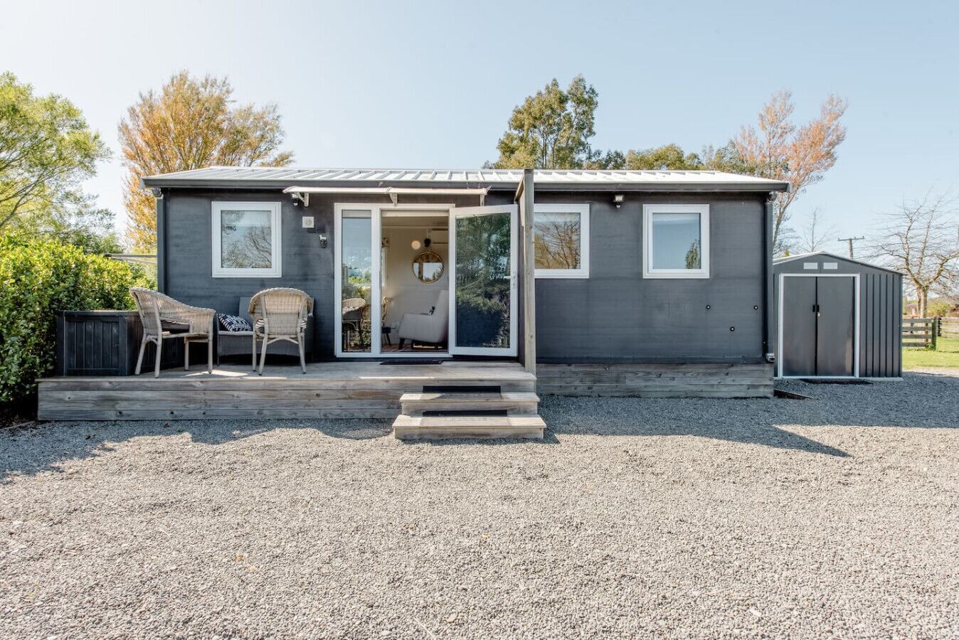 A single-story house with a front porch, a sliding glass door entrance, and a small deck area with outdoor furniture.