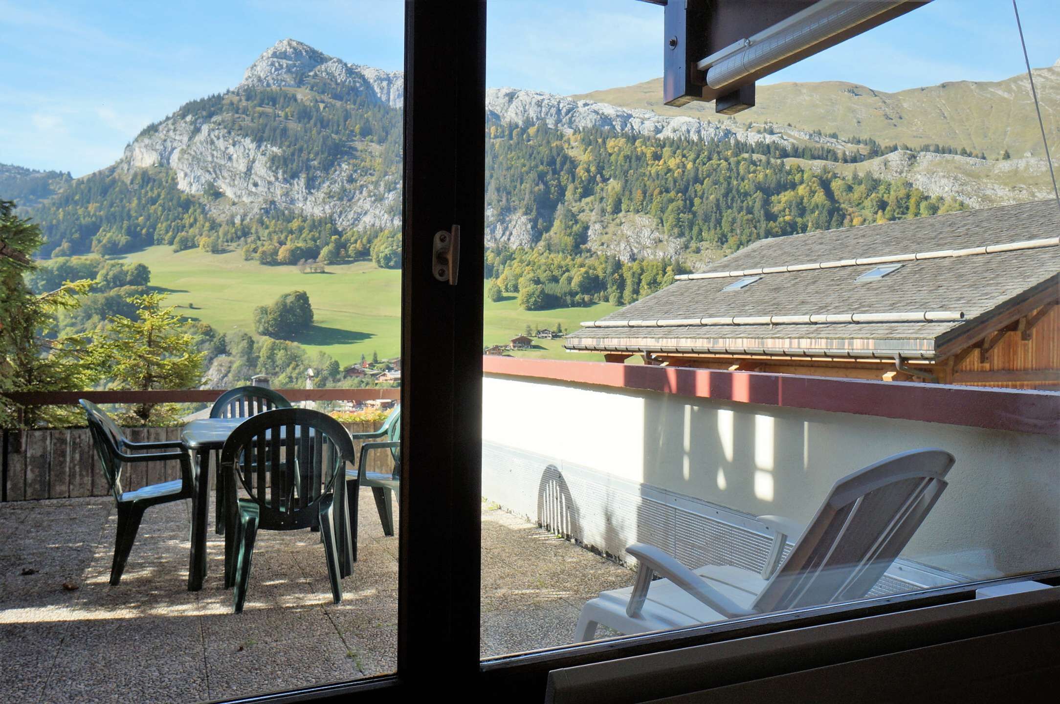 A view from a window overlooking a mountainous landscape with a building in the foreground.