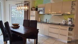 Una cocina moderna con una mesa y sillas, microondas y hervidor.