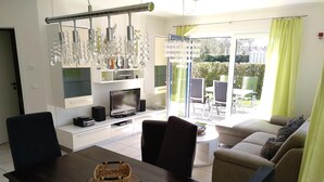 Una sala de estar moderna con televisor, asientos y zona de comedor.