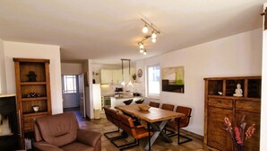 Amplia sala de estar con una mesa de comedor de madera, sofá de cuero marrón y una mesita de centro.