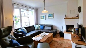 A living room with a sofa, a chair, a coffee table, a TV, and a fireplace. - Mine Heimat 15 "Dat Röverhus" - bright, friendly semi-detached house (Zingst)