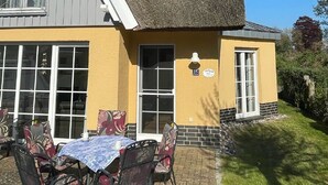 A building with a thatched roof, a yellow exterior, and a patio with outdoor seating. - Mine Heimat 15 "Dat Röverhus" - bright, friendly semi-detached house (Zingst)