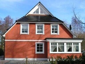 A two-story house with a red exterior, white trim, and a gabled roof.