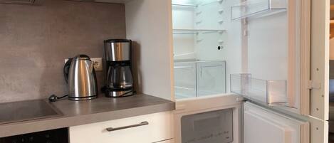 A modern kitchen with a built-in refrigerator, a coffee maker, and a kettle on the countertop.