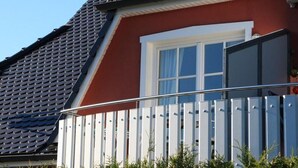 Une maison à l’extérieur rouge, avec une fenêtre blanche et une clôture blanche.