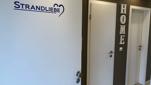 A hallway with a white door labeled "STRANDLIEBE" and another door labeled "HOME".