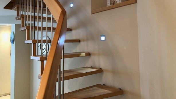 A wooden staircase with metal railings and built-in shelves on the walls.
