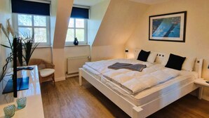 Ein Schlafzimmer mit einem großen Bett, einem Schreibtisch, einem Stuhl, einem Fenster mit Blick und einem Gemälde an der Wand.