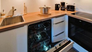 Eine kleine Küche mit Geschirrspüler, Backofen und Kaffeemaschine.