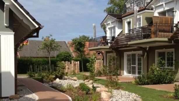 A residential property with a landscaped garden, a curved driveway, and a two-story house with a balcony. - Friedenstrasse 20b Whg. 9 "Haus Davide Classique" - exclusive and modern (Zingst)