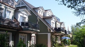 A row of townhouses with balconies, a well-maintained garden, and a clear sky. - Friedenstrasse 20b Whg. 9 "Haus Davide Classique" - exclusive and modern (Zingst)