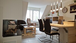A modern kitchen with a dining area, featuring a wooden table, chairs, and pendant lights. - Friedenstrasse 20b Whg. 9 "Haus Davide Classique" - exclusive and modern (Zingst)