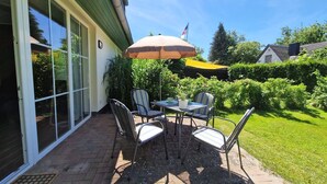 Une terrasse avec une table et des chaises, un drapeau et un jardin.