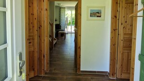 Un couloir avec des portes en bois, un sol carrelé et un luminaire au plafond.