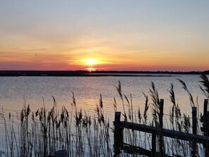 A sunset over a calm body of water with a wooden fence in the foreground.