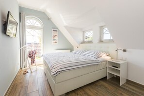 A bedroom with a bed, a nightstand, a window, and a view of the outside.