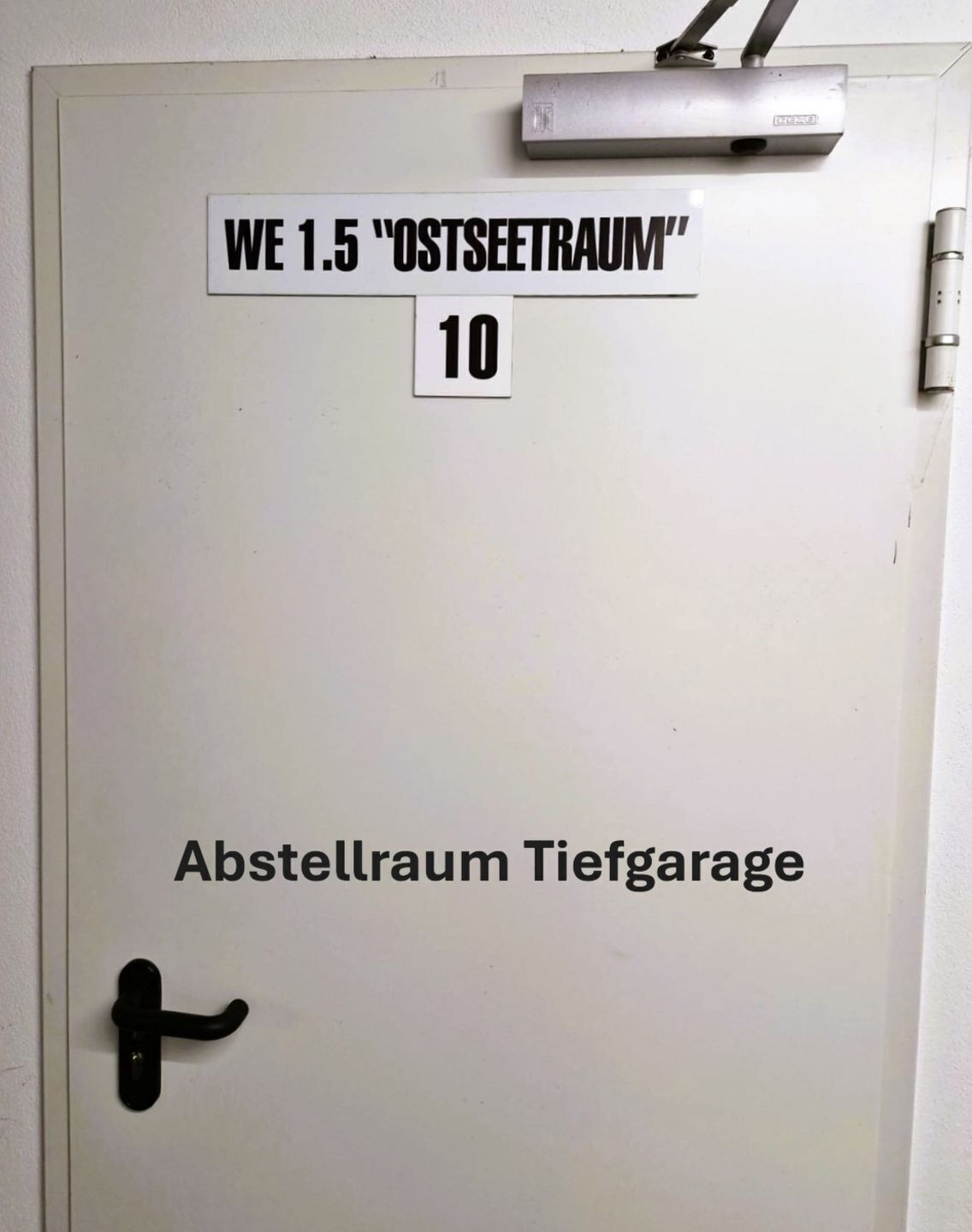 Una puerta con un letrero que dice "WE 1.5 'OSTSEETRAUM' 10" y "Abstellraum Tiefgarage".
